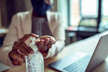 Close up businesswoman using hand sanitizer in office