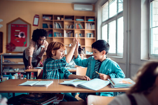 Young boys high fiving in elementary classroom - Powered by Adobe