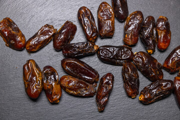 Sweet, dried dates on a black stone slab. Healthy food from the east, natural and healthy nutrition.
