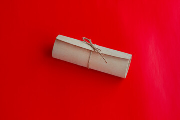 A close-up of a gift wrap with a twine bow on a red background. Greeting card background, letter with congratulations