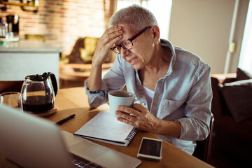 Senior woman having headache while working from home