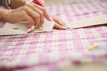 Woman in a workshop traces a pattern with chalk