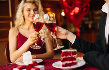 Young couple  celebrating  Valentine's Day with glass of red wine in the restaurant. Relationship, surprise and love concept.