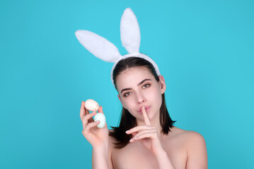 Obraz na płótnie Canvas Woman with bunny ears and easter eggs. Easter bunny isolated on studio background. Holidays, spring and party concept. Portrait of cute girl celebrating Easter.
