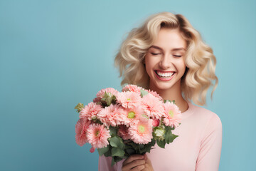 Happy woman with blonde hair holding spring flowers and smiling on pastel blue background, 8 March, Woman's day, birthday, Mother's day present	