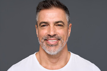 Happy confident handsome healthy mature older man, smiling middle aged male model wearing white t-shirt standing isolated on gray background advertising skin care and dental smile concept. - obrazy, fototapety, plakaty