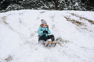 Little girl, happy child rides, sleds down the hill in the snow in winter. Photography, portrait, childhood concept, lifestyle.