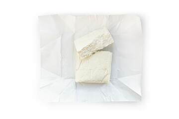 A briquette of fresh cottage cheese lies on a paper backing isolated on a transparent background.