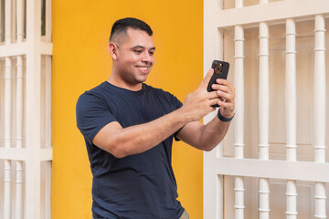 Joyful Man Taking a Selfie in Front of a Yellow Wall