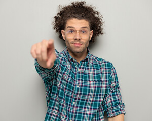 handsome man with curly hair looking forward and pointing finger forward