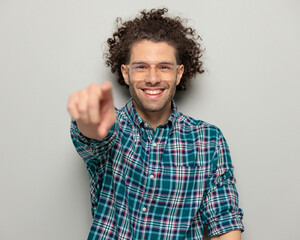 happy casual man with glasses smiling and pointing finger forward