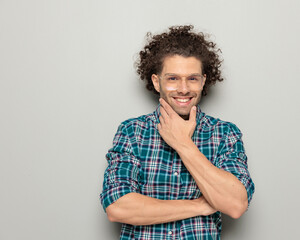 happy man with curly hair folding arms, touching chin and dreaming