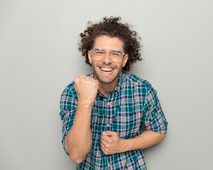 cheerful attractive man with glasses celebrating victory and laughing