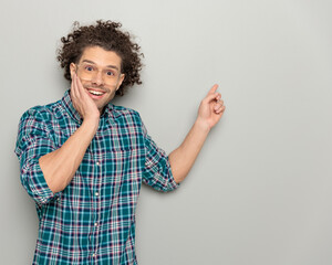 happy casual man with glasses pointing finger to side and showing