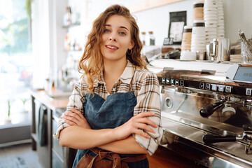 Portrait of a beautiful barista girl in an apron in a modern cafe bar. Startup successful small business owner  beauty woman stand in coffee shop restaurant. Business concept.