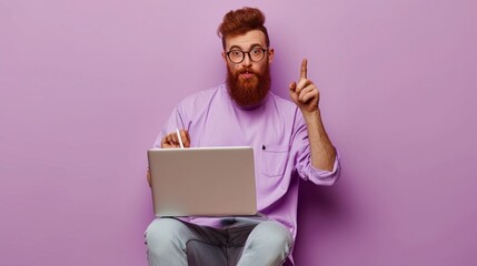 Full body young redhead bearded man in violet t-shirt casual clothes sitting hold use work on laptop pc computer point aside isolated on plain pastel light purple background studio Lifestyle concept - obrazy, fototapety, plakaty