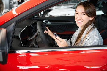 Smiling woman sitting in new automobile enjoying her purchase in dealership