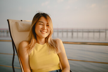 Happy Asian woman sits and relaxed enjoy sunset sea view of her honeymoon.