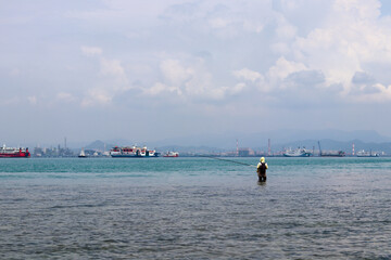 a fisherman who is fishing in the turquoise open sea
