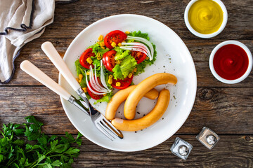 Breakfast - boiled sausages and fresh vegetables served on wooden table
