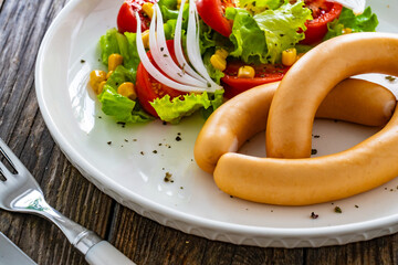 Breakfast - boiled sausages and fresh vegetables served on wooden table