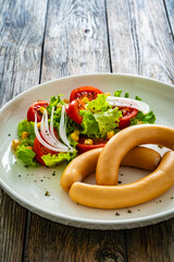 Breakfast - boiled sausages and fresh vegetables served on wooden table