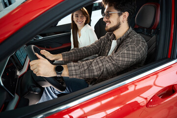 Man and woman sitting in new car choosing their automobile in dealership