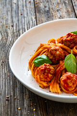 Spaghetti meatballs in bolognese sauce on wooden table