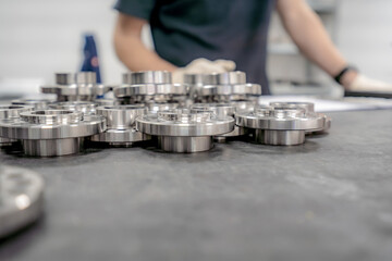 A worker inspects and sorts round parts with holes for assembling them into components and assemblies.