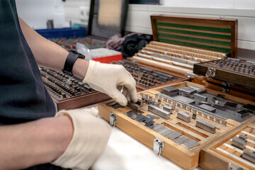 The worker selects gauge blocks to obtain the required control size of the part being manufactured and adjusts the measuring tool of a CNC metal-cutting machine.