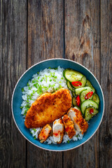 Tonkatsu - crispy Japanese pork chop with white rice and  fresh vegetables on wooden table