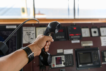 Navigational control panel and VHF radio with hand. Radio communication at sea. Working on the...