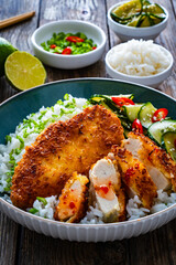 Tonkatsu - crispy Japanese pork chop with white rice and  fresh vegetables on wooden table