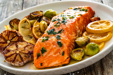 Fried salmon steak and garlic, brussels sprouts and lemon served on wooden table
