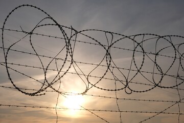 Barbed wire fence against the background of sunset sky