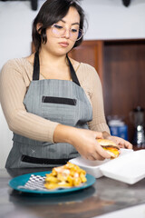 packing delicious burger with fries for home delivery, fast food in dark kitchen, person working in restaurant, lifestyle