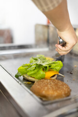 cooking a meat on the grill next to lettuce, ingredients for a hamburger, preparation of delicious foods, kitchen work place, wallpaper