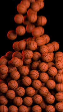 Many basketball balls falling from above against black background in slow motion. Lots of basketball balls, vertical video

