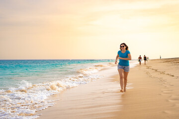 Beautiful woman running on sunny beach Santa Maria, Sal Island, Cape Verde
