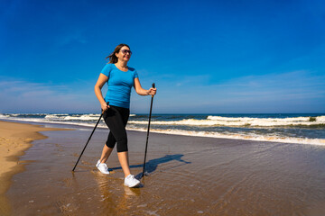 Nordic walking - beautiful woman exercising on beach
