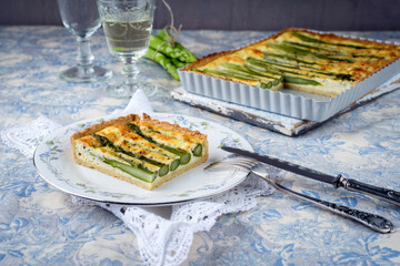 Traditional French vegetable tarte with green asparagus served as close-up in a backing backing...