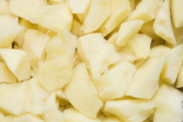 A close-up of freshly cut raw potatoes with small bubbles, soaking ready for cooking. Food preparation.