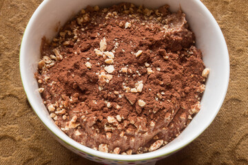 Overhead view of a bowl of creamy, homemade chocolate dessert, sprinkled with crushed almonds and...