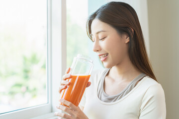Orange detox juice, smile asian young woman hand holding glass of vegetable juice, carrot smoothie...