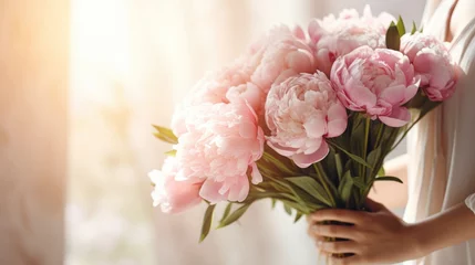 Foto op Plexiglas Women's hands holding a bouquet of pink peonies for congratulations on Mother's Day, Valentine's Day, women's Day. Blurred background. © Cherkasova Alie