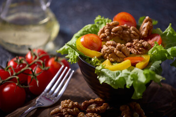 Vegetarian healthy breakfast, snack or lunch consisting of a salad of fresh vegetables and walnuts, seasoned with vegetable oil. Fresh ripe vegetables on a beautiful table with walnuts and tomatoes