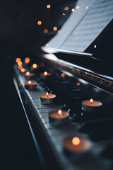 Burning candles stay on vintage piano keys over glow lights at background. Romantic atmosphere.