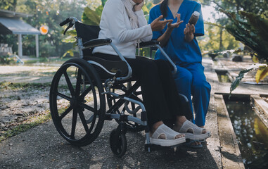 nurse with elderly man in wheelchair at park