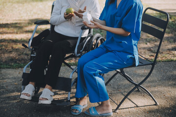 Obraz premium nurse with elderly man in wheelchair at park