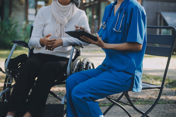 Obraz premium nurse with elderly man in wheelchair at park